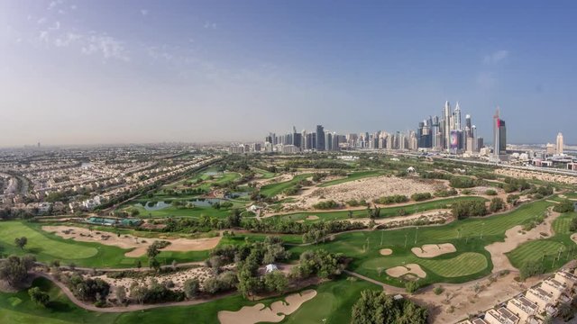 Dubai Marina with JLT skyscrapers and golf course morning timelapse, Dubai, United Arab Emirates. Aerial view from Greens district. Green lawn and cloudy sky