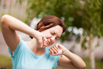 Tired young woman yawn and want to sleep, outdoors in summer