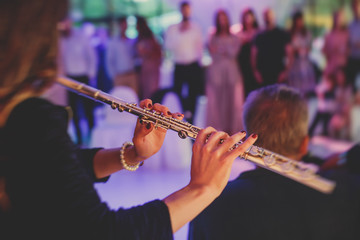 Concert view of a flutist flute player with musical jazz band and audience in the background