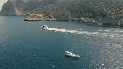 Aerial View of yacht near rocky island of Mallorca. Drone footage of yachting around Balearic islands in the mediterranean sea 