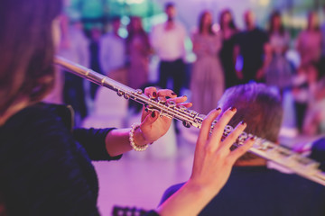 Concert view of a flutist flute player with musical jazz band and audience in the background