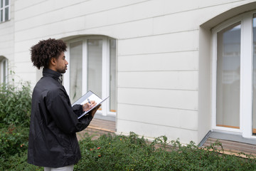 Person Filling Document In Front Of House