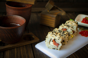 Sesame seeds roll sushi with red caviar, dark wooden table