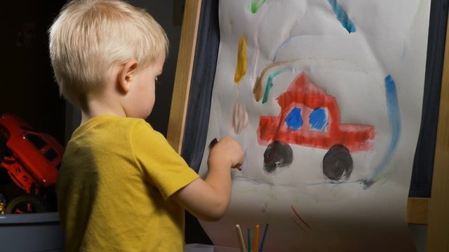 Little boy (preschooler) is painting  with watercolor paint. Indoor kids activities, daycare, classroom. Early education concept, child creativity and art