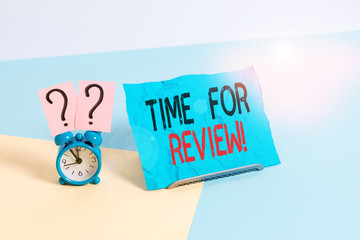 Conceptual hand writing showing Time For Review. Concept meaning formal assessment of something with intention instituting change Alarm clock beside a Paper sheet placed on pastel backdrop