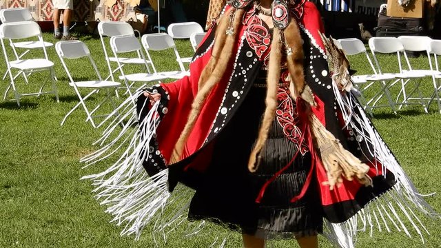 Barefoot Native American Indian First Nations Woman Dancing On Grass In Red Dress With Feather Fan