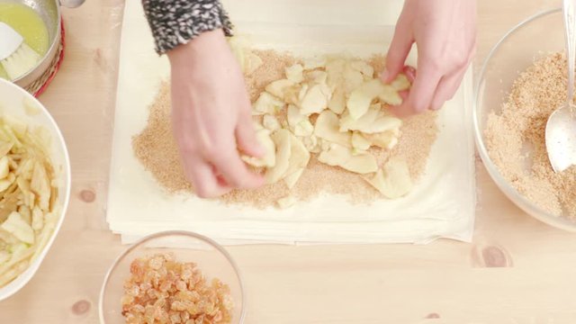 Woman's hands putting apples over phyllo dough to make Viennese strudel
