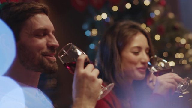 Pretty romantic couple toasting wine clinking glasses enjoying drinks laughing celebrating Christmas holiday with friends. Happy best friends reunion party.