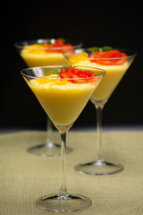 Vanilla Pudding with lemon and strawberry garnish in Martini glass with black background.