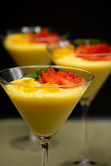 Vanilla Pudding with lemon and strawberry garnish in Martini glass with black background.