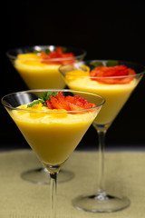 Vanilla Pudding with lemon and strawberry garnish in Martini glass with black background.