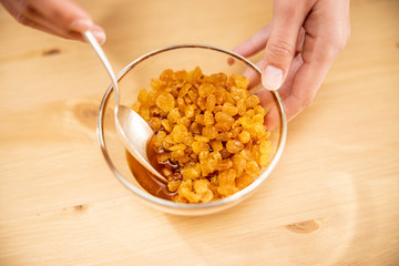 Close up of woman's hands stirring raisins and rum in glass bowl