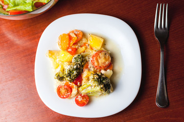 White plate with cooked vegetables on kitchen table. Healthy eating