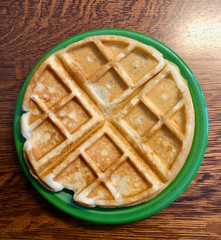 Golden waffle on green plate for breakfast on wooden table