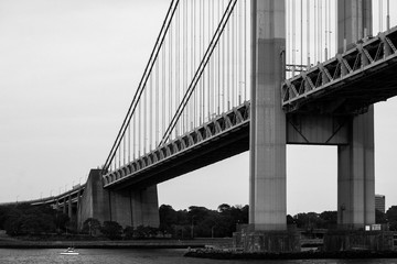 Greyscale of the Manhattan bridge in New York surrounded by water and greenery
