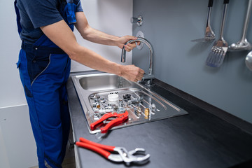 Plumber Fixing Faucet In Kitchen