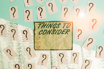 Writing note showing Things To Consider. Business concept for think about carefully especially in making decisions Scribbled and crumbling papers with thick cardboard above wooden table