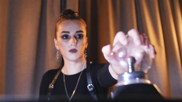 girl puts her hand on a magical electra ball in a sword belt and black eyes