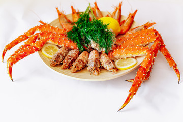 Red king crab and shrimp on a plate with lemon and dill. White background