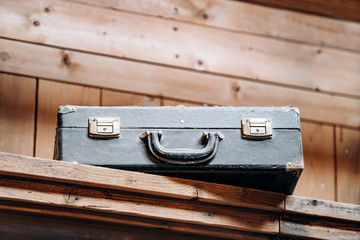An old battered suitcase on a shelf in the dust. Vintage travel bags are on a shelf. Retro bulky Luggage. Image done in grunge style on rough dirty texture background