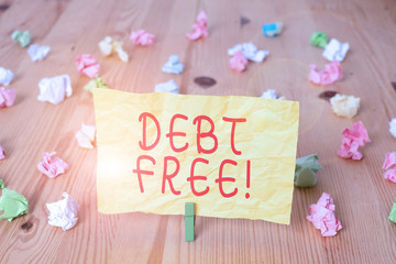 Writing note showing Debt Free. Business concept for does not owning any money or things to any individual or companies Colored crumpled papers wooden floor background clothespin