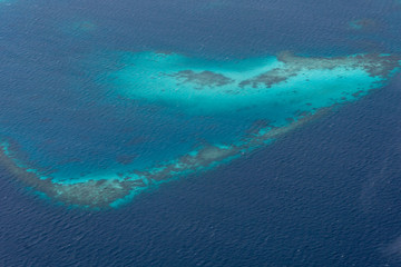 Fototapeta na wymiar Islands view from the window of the plane. Beautiful atolls and bright colors of the sea