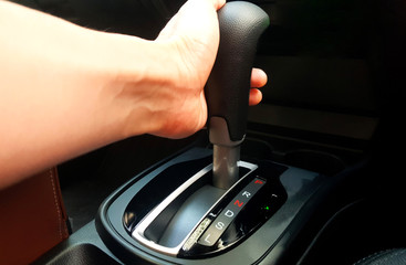 The hands of the young man driving and controlling the automatic car gear