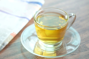 Cup of green tea hot on the desk has a newspaper and a tablet. at office