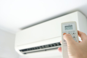 Man's hand using remote control open The air conditioner is cooled to 25 degrees Celsius in his bedroom. Health concepts and energy savings