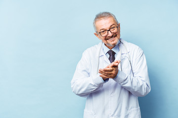 Smiling medical senior doctor with a stethoscope. On a blue background. Medic shows thumb raised up. The concept of humanity's victory over disease