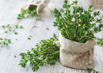 Fresh green thyme in decorative linen bag on an old wooden table. - obrazy, fototapety, plakaty