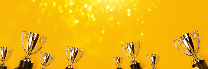 Champion cups on yellow background with sparkling lite. Tha winner takes it all! - 309512352