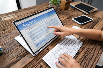 Fototapeta na wymiar Businessperson Filling Online Survey Form On Laptop
