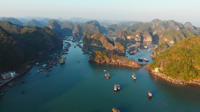 Aerial: sunset clear sky at Cat Ba island and Lan Ha bay, the biggest island in Ha Long Bay. Floating fishermen villages and markets among unique limestone rock peaks in the sea, Vietnam