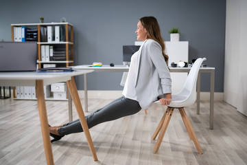 Businesswoman Doing Triceps Dips In Office