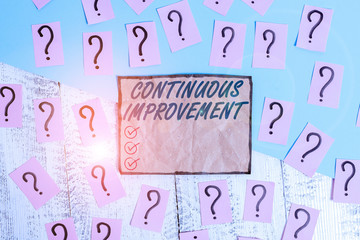 Writing note showing Continuous Improvement. Business concept for ongoing effort to improve products or processes Scribbled and crumbling papers with thick cardboard above wooden table
