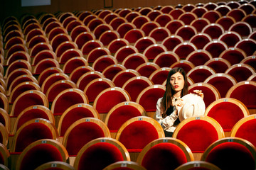 portrait of a pretty girl hipster in a movie theater posing in fashion style, dreaming alone
