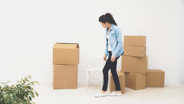 Strong woman is carring a large moving box, full of items, isolated on white background. 4K.
