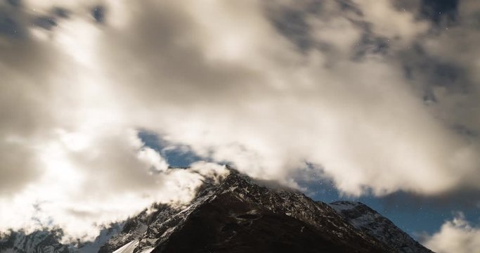Time lapse of stars and clouds clearing over mountain revealing full moon over peaks of Himalayas, Manaslu region, Nepal