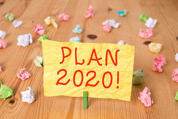 Writing note showing Plan 2020. Business concept for detailed proposal doing achieving something next year Colored crumpled papers wooden floor background clothespin