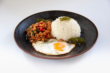 Favorites Thai food, Jasmine rice with organics stir-fried pork holy basils and fried egg served in black dish on white background, Isolated image.