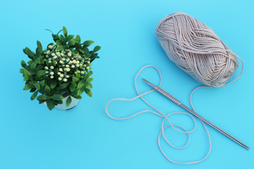 Skeins of gray yarn and knitting needles on blue background