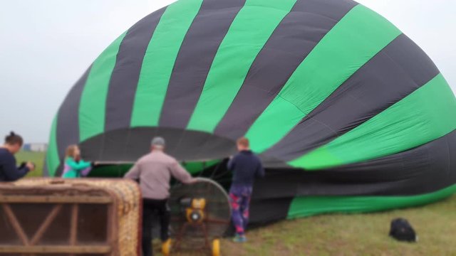 Inflating, unpack and flying up hot air balloon watermelon. Burner directing flame into envelope. Take off aircraft fly in morning blue sky. Start hot air burning to inflate gas fire to air balloon.