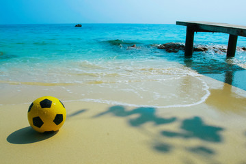 Fototapeta na wymiar yellow ball on beach with blue sea background