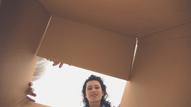 The girl and the boy are unpacking and looking at the box. View from inside the box. Close-up. Copy space. 4K.