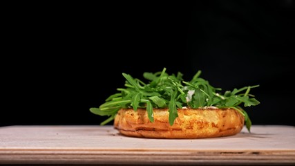 Craft burger is cooking on black background in black food gloves. Consist: sauce, arugula, tomato, red onion rings fries, cucumber, cheese, air bun and marble meat beef. Not made ideal. Looks real