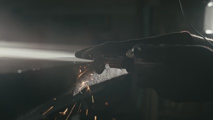 Forge. Smithy. Glass cutting and processing for fireplace doors. Circular glass cutter. Worker cut glass with glass cutting diamond. Polish an angle grinder with an abrasive circular disk nozzle.