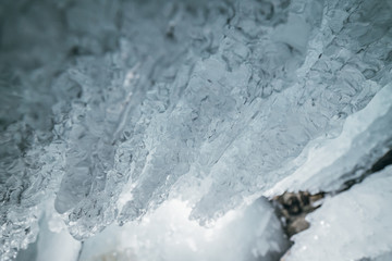 Winter Baikal. Olkhon Island. Ice grotto. Thick blue ice and icicles on the coastal rocks of Olkhon Island in winter. Natural cold background. The winter the lake and the surrounding area becomes ice.