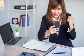 An Asian businesswoman looks happy while looking at the information on the phone.