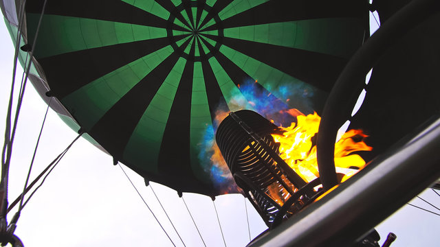 Adventure on hot air balloon watermelon. Burner directing flame into envelope. The aircraft fly in morning blue sky due to hot air. Hot air burning gas fire to air balloon or aerostat during flight.